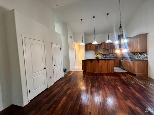 3205 Petite Sirah St, Bakersfield, CA 93306 - kitchen with high vaulted ceiling, brown cabinetry, dark wood-style flooring, dark countertops, and glass insert cabinets
