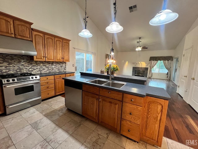 3205 Petite Sirah St, Bakersfield, CA 93306 - kitchen featuring stainless steel appliances, under cabinet range hood, dark countertops, brown cabinets, and backsplash
