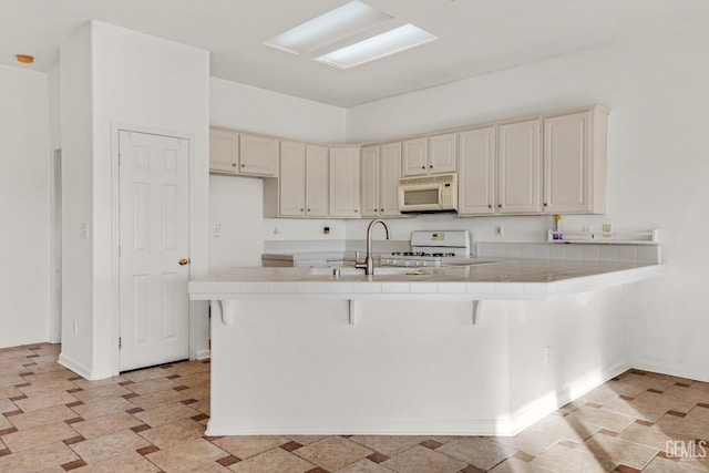 kitchen featuring tile counters, white appliances, and a breakfast bar