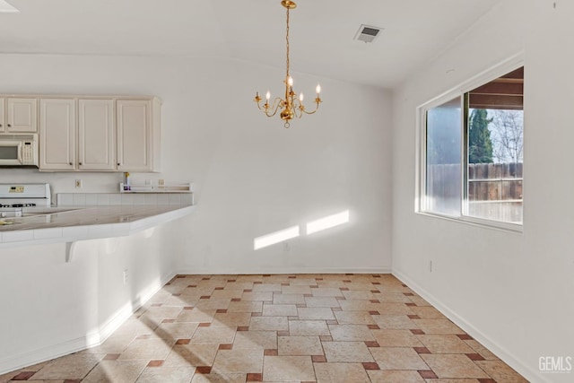 kitchen with white appliances, vaulted ceiling, sink, a notable chandelier, and tile counters