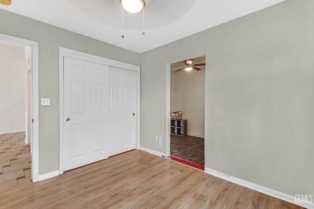 unfurnished bedroom with hardwood / wood-style flooring, ceiling fan, and a closet