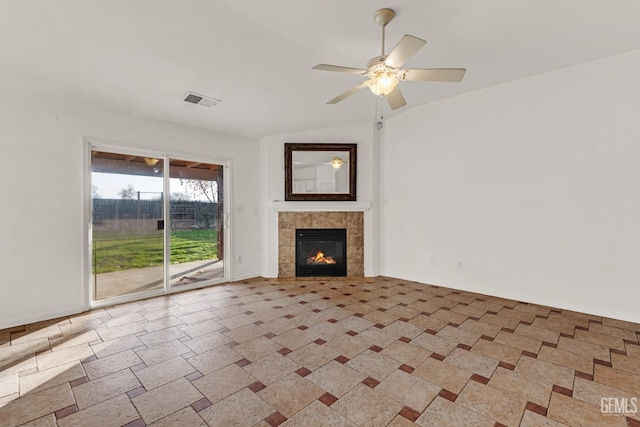 unfurnished living room with a tile fireplace, ceiling fan, and vaulted ceiling