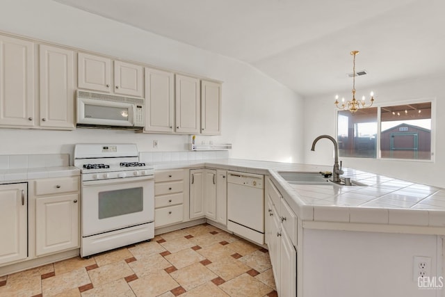 kitchen featuring tile counters, sink, an inviting chandelier, kitchen peninsula, and white appliances