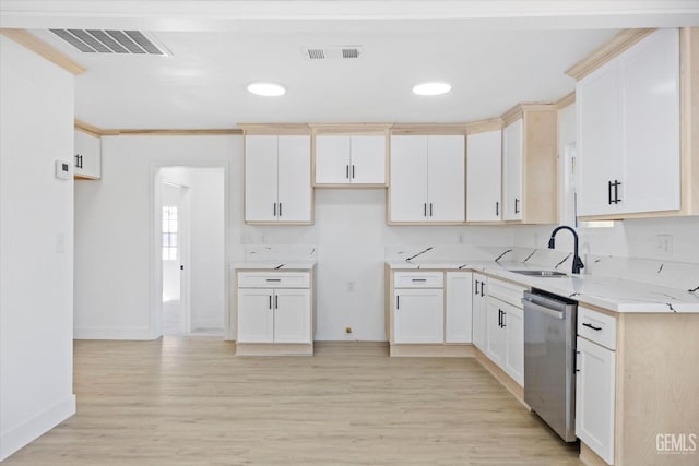 kitchen with sink, white cabinets, light wood-type flooring, stainless steel dishwasher, and light stone countertops