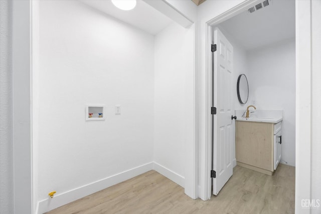 clothes washing area featuring hookup for a washing machine and light hardwood / wood-style floors