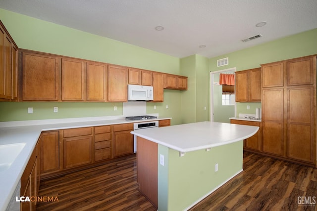 kitchen with visible vents, white appliances, brown cabinets, and dark wood-style floors