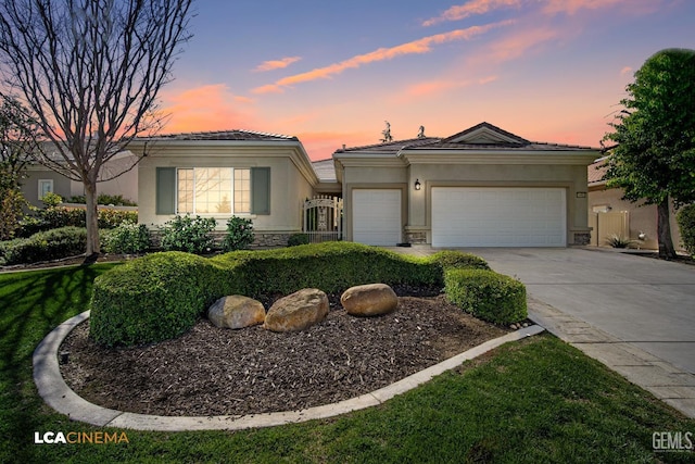 view of front of home with stucco siding, driveway, stone siding, an attached garage, and a tiled roof