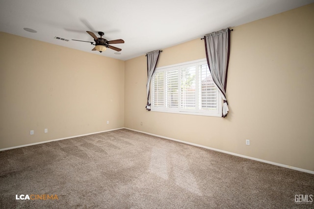 empty room with carpet flooring, a ceiling fan, visible vents, and baseboards