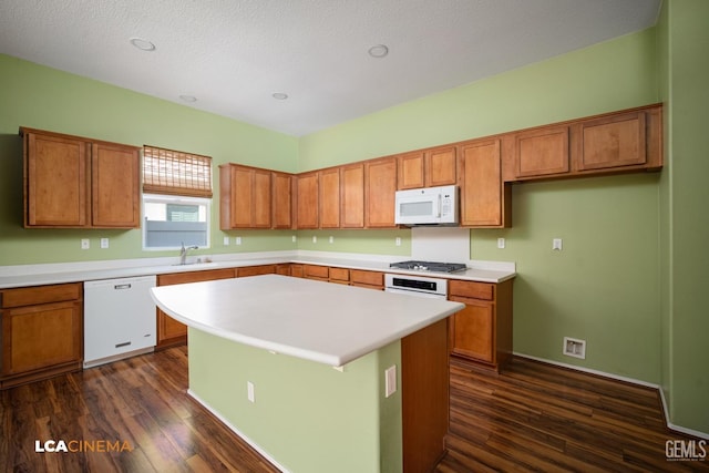 kitchen with white appliances, brown cabinetry, and a sink