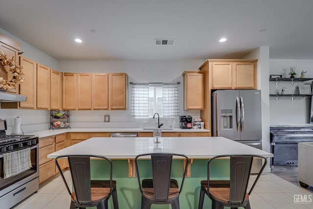 kitchen featuring light brown cabinetry, light tile patterned floors, appliances with stainless steel finishes, and a sink