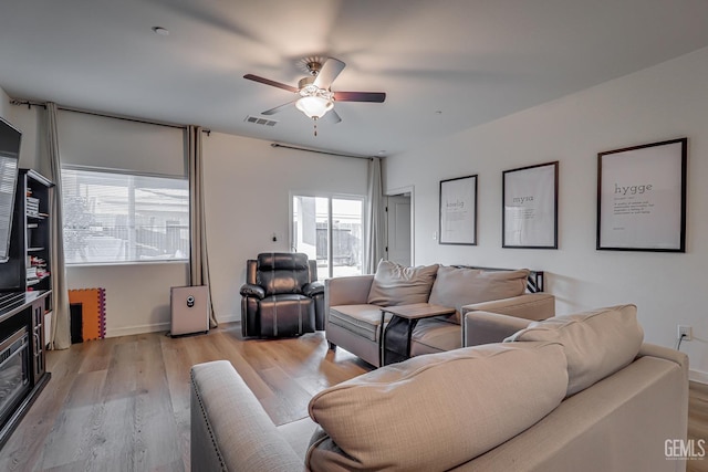 living area with visible vents, baseboards, a ceiling fan, and light wood finished floors