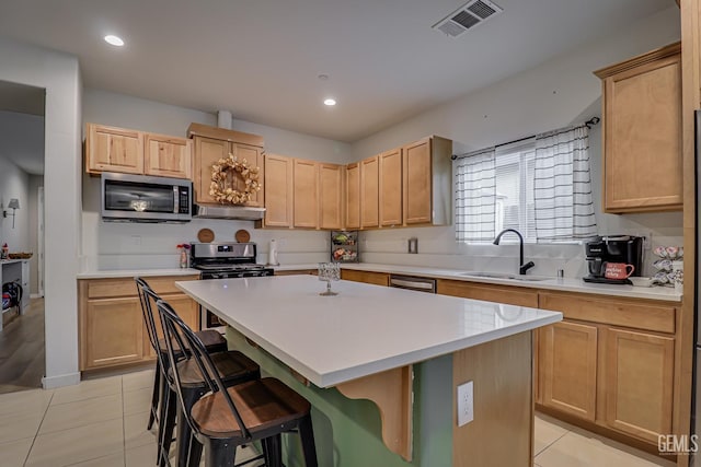 kitchen with visible vents, light brown cabinets, under cabinet range hood, appliances with stainless steel finishes, and a sink