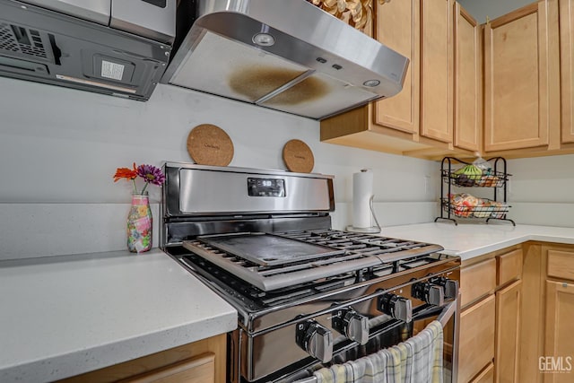 kitchen with gas range, exhaust hood, light brown cabinets, and light countertops