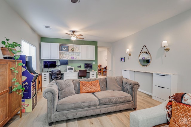 living area with visible vents, light wood-style floors, and a ceiling fan