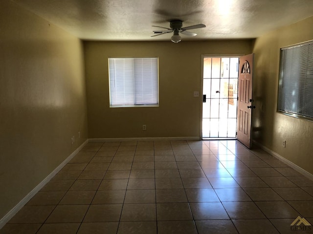 tiled spare room with a textured ceiling and ceiling fan