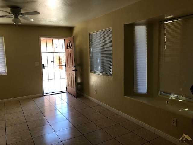 doorway with ceiling fan and tile patterned flooring