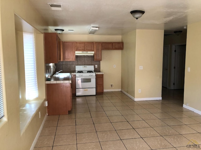 kitchen with tasteful backsplash, sink, light tile patterned floors, tile counters, and white gas range oven