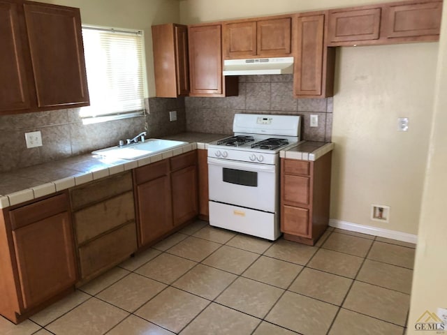 kitchen featuring tasteful backsplash, sink, white range with gas cooktop, tile counters, and light tile patterned floors