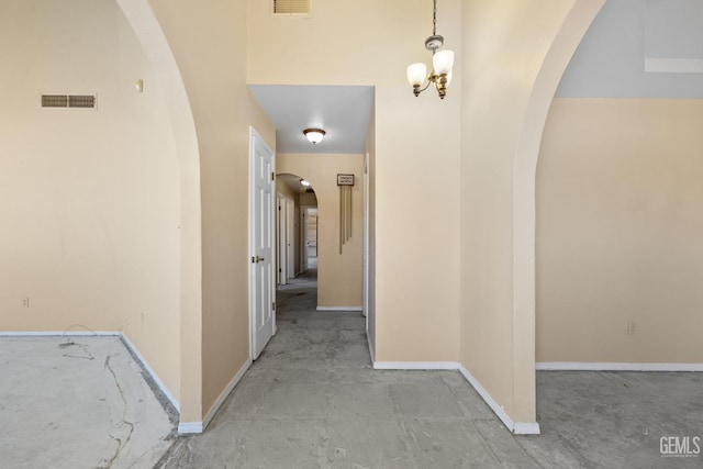 hallway featuring arched walkways, baseboards, and a chandelier