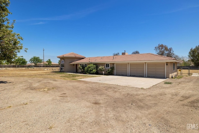 view of front of home featuring a tiled roof, a chimney, driveway, stucco siding, and fence