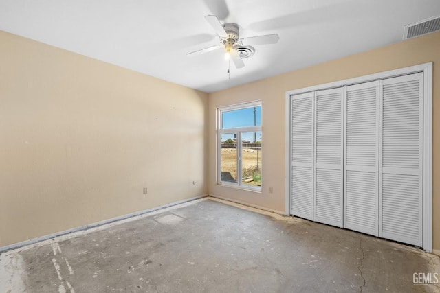 unfurnished bedroom with concrete flooring, a closet, baseboards, and ceiling fan