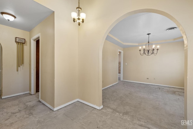 spare room with a chandelier, concrete floors, arched walkways, and baseboards