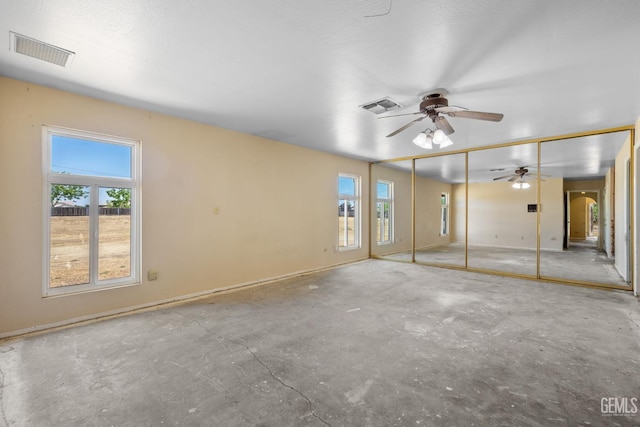 unfurnished bedroom with multiple windows, unfinished concrete floors, and arched walkways