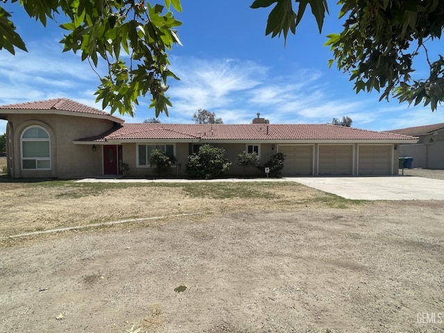 view of front of property with a tile roof, concrete driveway, an attached garage, and stucco siding
