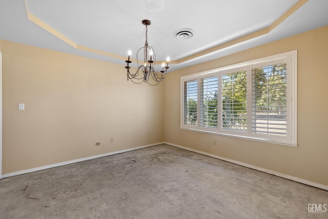 spare room with a raised ceiling, a chandelier, unfinished concrete floors, and baseboards