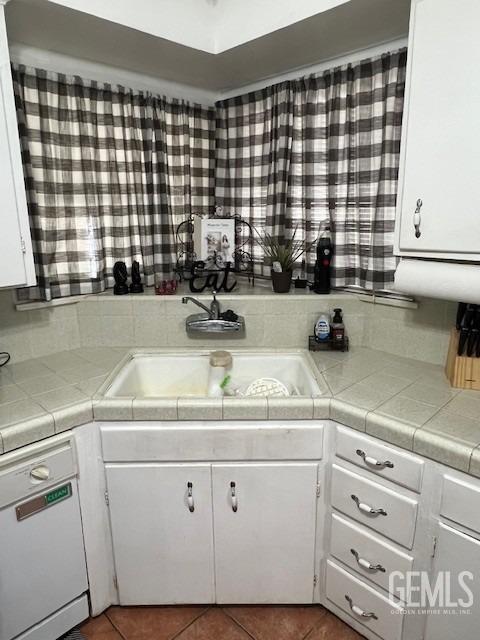 2320 Olympic Dr, Bakersfield, CA 93308 - kitchen with dishwasher, tile patterned floors, white cabinetry, a sink, and tile countertops