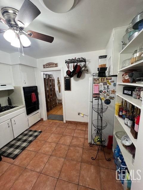 2320 Olympic Dr, Bakersfield, CA 93308 - kitchen featuring white cabinets, tile patterned floors, a ceiling fan, under cabinet range hood, and black appliances