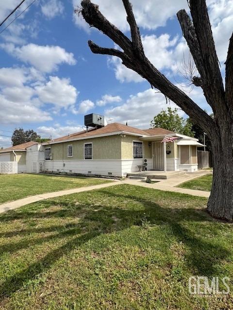 2320 Olympic Dr, Bakersfield, CA 93308 - rear view of house with stucco siding, crawl space, central AC unit, and a lawn