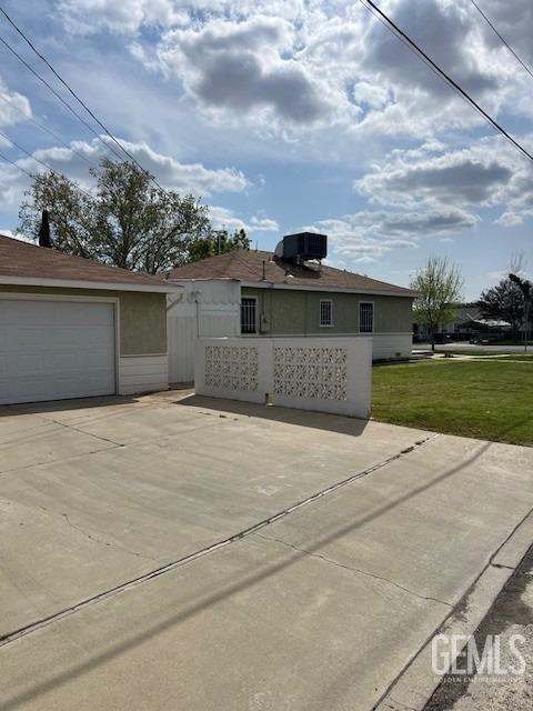 2320 Olympic Dr, Bakersfield, CA 93308 - exterior space with an outdoor structure, stucco siding, central air condition unit, a front lawn, and a garage