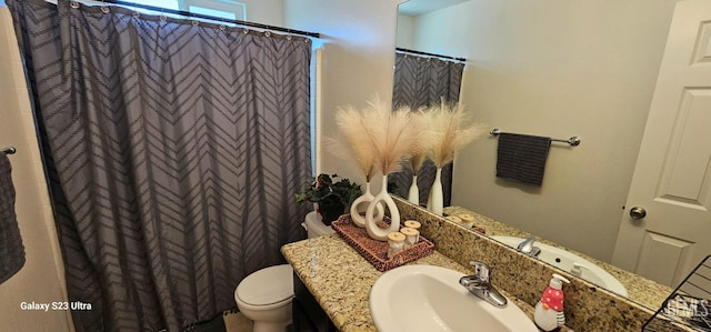 bathroom featuring toilet, curtained shower, and vanity