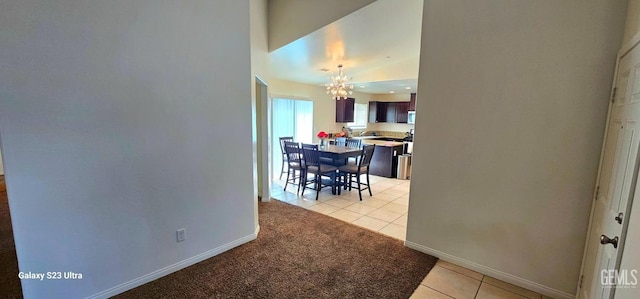 dining space featuring light carpet, light tile patterned floors, a notable chandelier, and baseboards