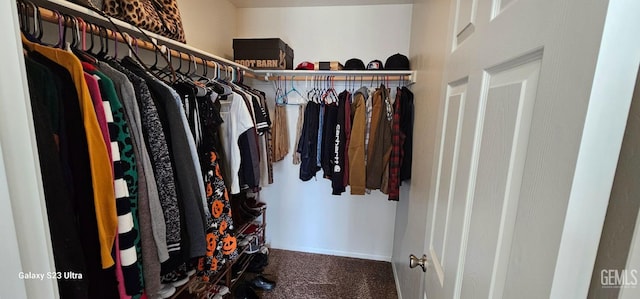 walk in closet featuring dark colored carpet