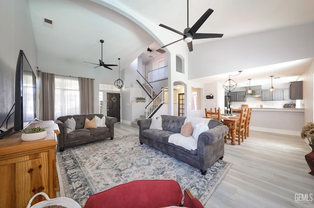 8315 Persimmon Dr, Bakersfield, CA 93311 - living room featuring a ceiling fan, high vaulted ceiling, light wood finished floors, stairs, and arched walkways