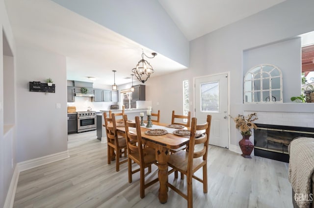 8315 Persimmon Dr, Bakersfield, CA 93311 - dining room with light wood-style floors, a fireplace, a chandelier, and high vaulted ceiling