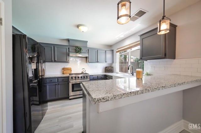 8315 Persimmon Dr, Bakersfield, CA 93311 - kitchen with high end stainless steel range oven, black fridge with ice dispenser, a peninsula, tasteful backsplash, and light wood-style flooring