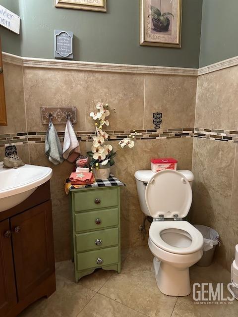 half bathroom featuring vanity, toilet, and tile walls