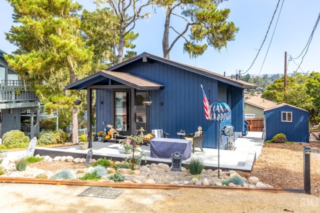 view of front of property with a patio and a storage shed