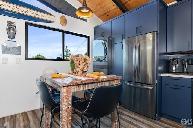 kitchen featuring blue cabinetry, stacked washer and clothes dryer, wood ceiling, stainless steel fridge, and backsplash