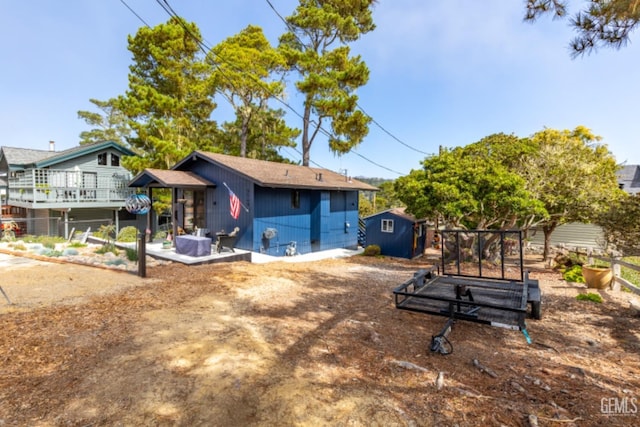 back of house with a storage unit