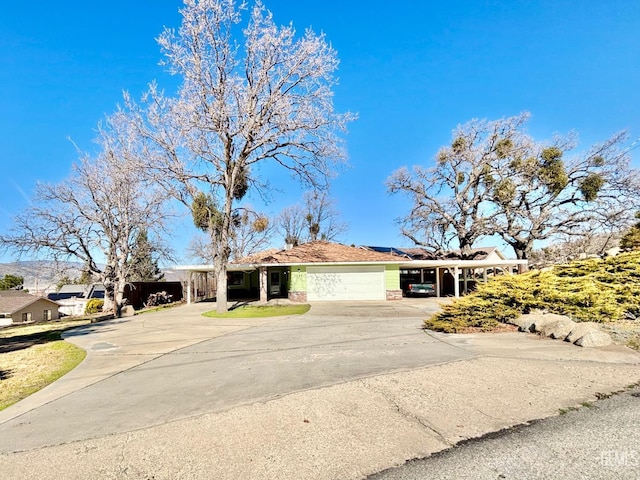 ranch-style house with a garage, concrete driveway, an attached carport, and solar panels