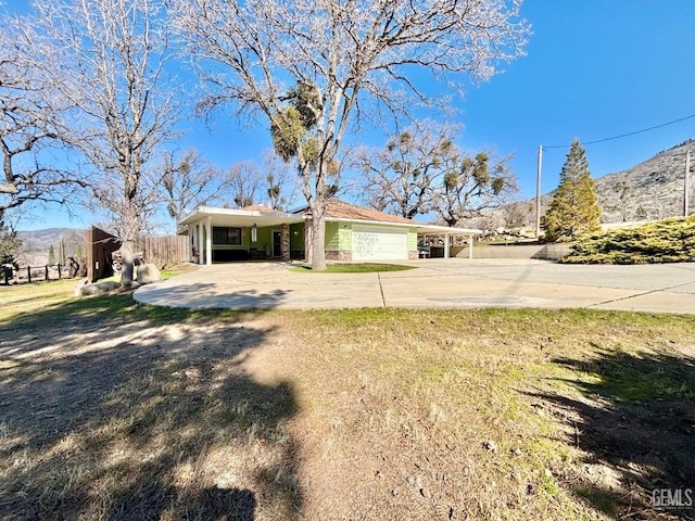 view of front of home featuring a garage, concrete driveway, fence, and a mountain view