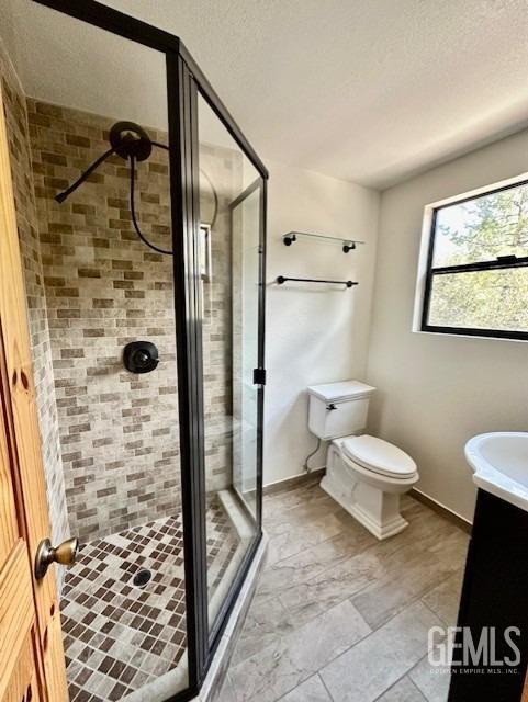 bathroom with toilet, a stall shower, baseboards, and vanity