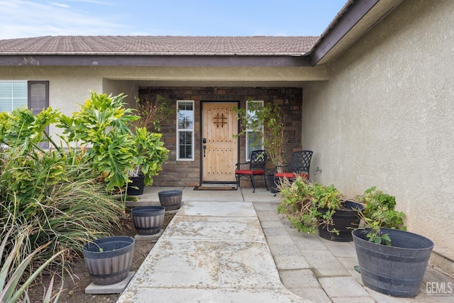 doorway to property featuring stone siding, a tiled roof, and stucco siding