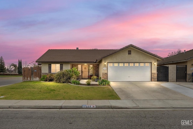 ranch-style house with driveway, stone siding, an attached garage, a gate, and stucco siding