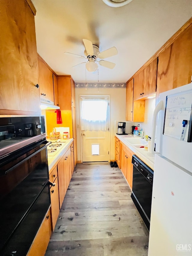 kitchen featuring black appliances, sink, light hardwood / wood-style flooring, backsplash, and ceiling fan