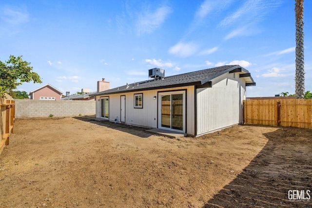 back of house with a fenced backyard, central AC unit, and roof with shingles